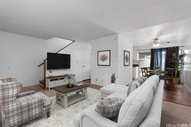 living area with baseboards, a ceiling fan, and wood finished floors