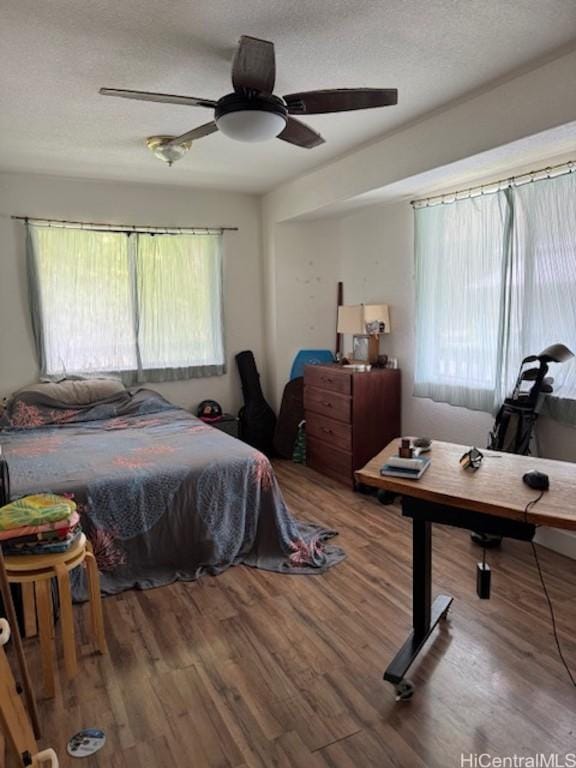 bedroom with a textured ceiling, multiple windows, and wood finished floors