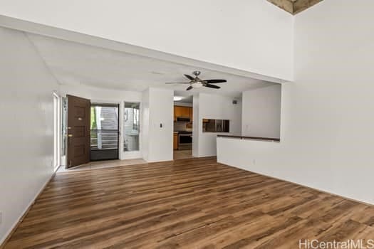 unfurnished living room with beamed ceiling, wood finished floors, and a ceiling fan