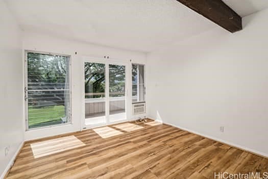 empty room featuring wood finished floors and beamed ceiling