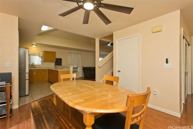 dining space featuring wood finished floors, ceiling fan, baseboards, and stairs