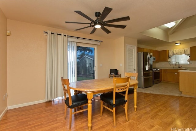 dining room with vaulted ceiling, light wood-style flooring, baseboards, and ceiling fan