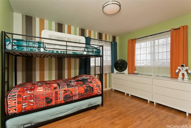 bedroom with wood finished floors and wallpapered walls