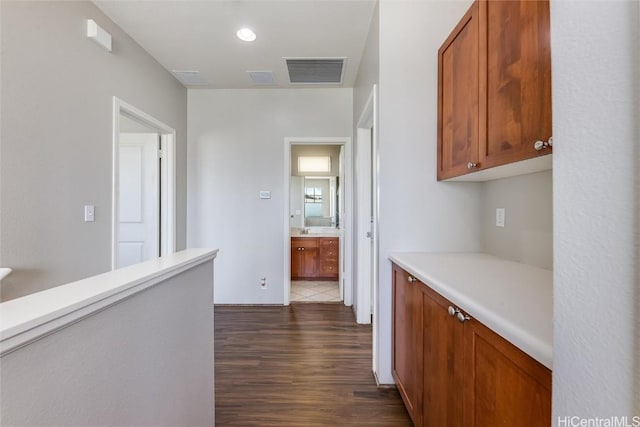 hall with dark wood-style floors, visible vents, and recessed lighting