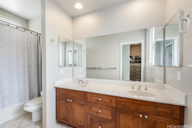 bathroom with toilet, double vanity, a sink, and tile patterned floors