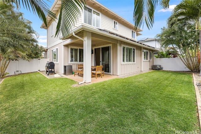 rear view of house with board and batten siding, a fenced backyard, a lawn, and central AC