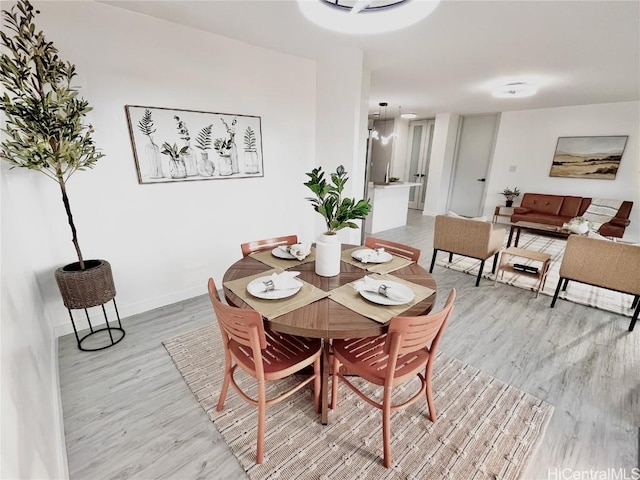 dining space featuring baseboards and light wood finished floors