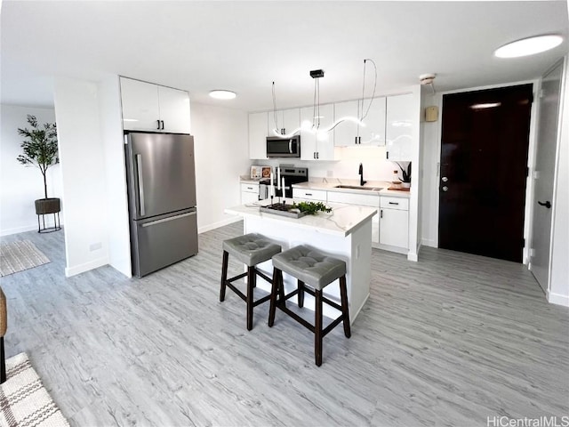 kitchen with light countertops, appliances with stainless steel finishes, light wood-type flooring, and a sink