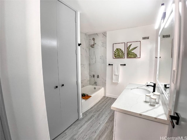 bathroom featuring visible vents, shower / bathing tub combination, wood finished floors, and vanity