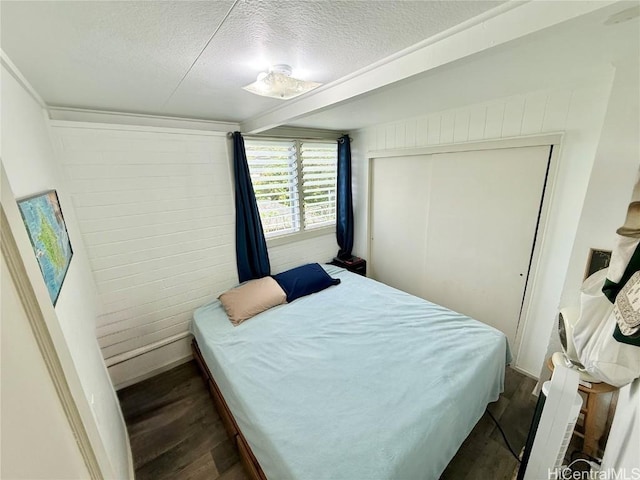 bedroom with a textured ceiling, a closet, and dark wood finished floors