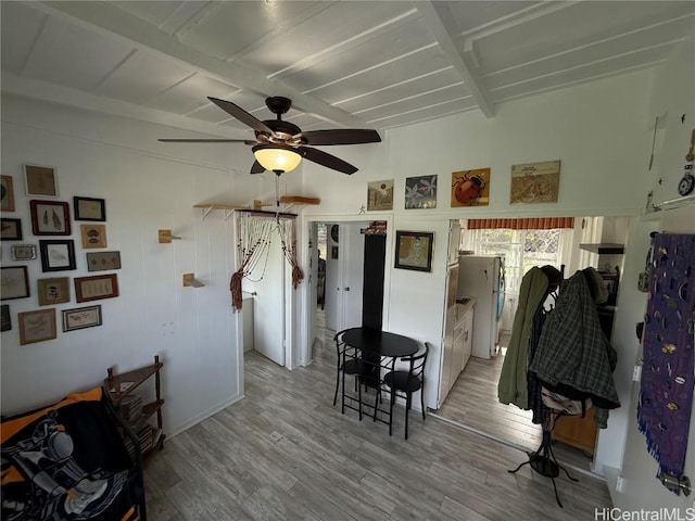 dining space with a ceiling fan, beam ceiling, and light wood-style flooring