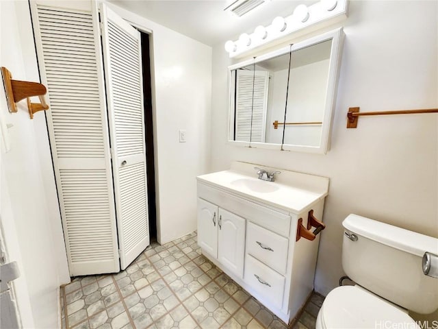 bathroom with visible vents, toilet, a closet, and vanity