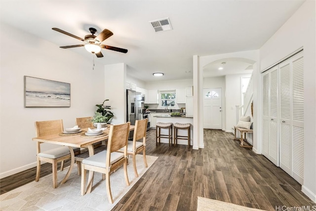 dining space with arched walkways, visible vents, dark wood-style flooring, and baseboards