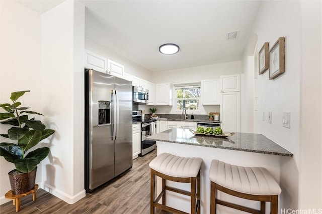 kitchen with visible vents, a breakfast bar, a peninsula, stainless steel appliances, and a sink