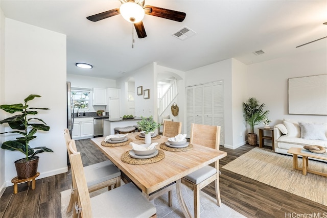 dining area featuring visible vents, baseboards, ceiling fan, dark wood finished floors, and stairs