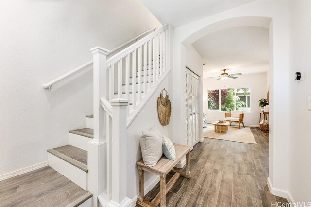 stairs featuring wood finished floors, arched walkways, and baseboards