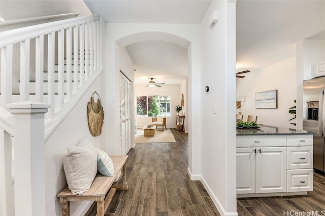 hall with baseboards, arched walkways, and dark wood finished floors