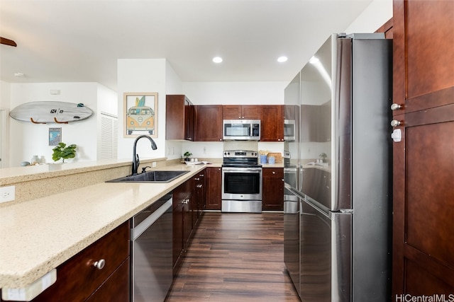 kitchen featuring dark wood-style floors, light stone countertops, recessed lighting, a sink, and stainless steel appliances