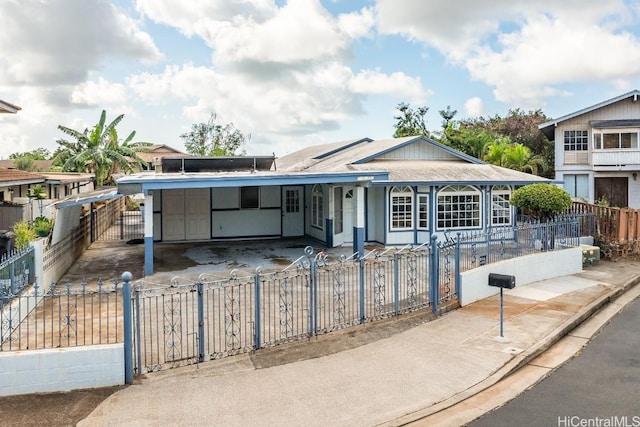 view of front of property featuring a fenced front yard, driveway, and a carport