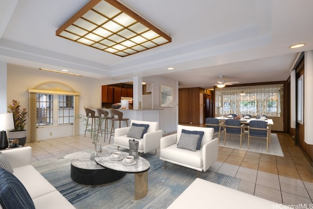 living room with recessed lighting, a raised ceiling, and light tile patterned floors