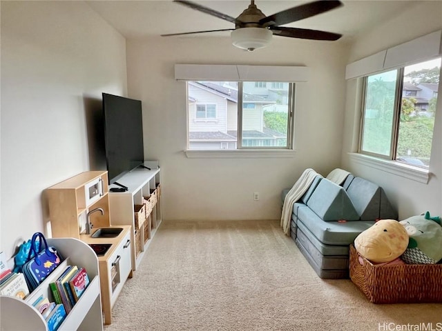 game room with ceiling fan, a sink, and light colored carpet