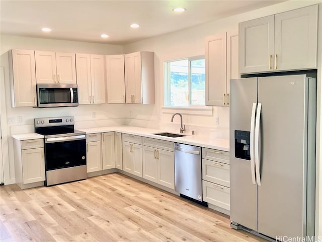 kitchen featuring a sink, recessed lighting, stainless steel appliances, light wood-style floors, and light countertops