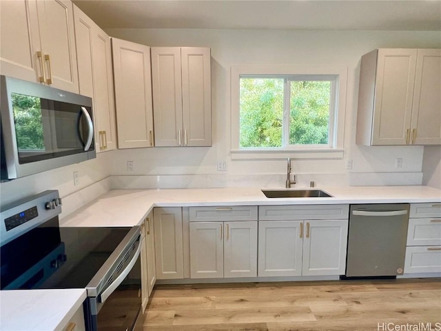 kitchen featuring light countertops, light wood finished floors, appliances with stainless steel finishes, and a sink