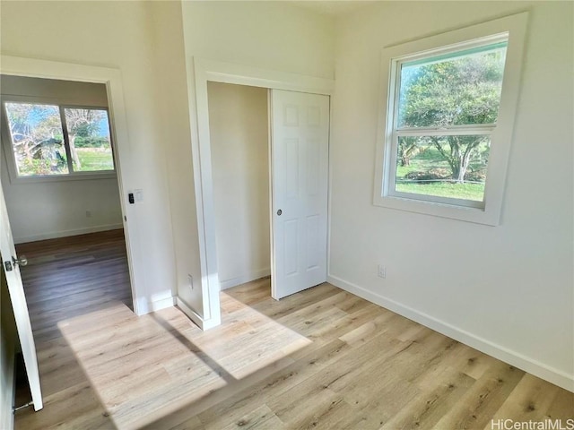 unfurnished bedroom featuring light wood-style floors, a closet, and baseboards