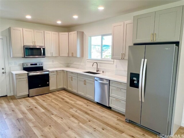 kitchen with light countertops, recessed lighting, light wood-style floors, stainless steel appliances, and a sink