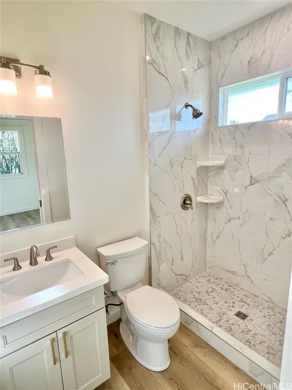 full bathroom featuring a marble finish shower, toilet, wood finished floors, and vanity