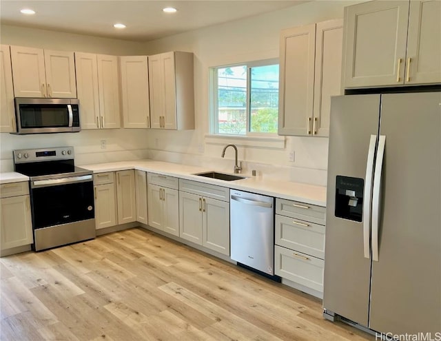 kitchen featuring light wood-type flooring, light countertops, recessed lighting, stainless steel appliances, and a sink