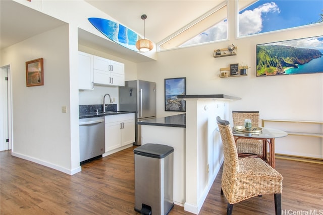 kitchen with stainless steel appliances, dark wood-style flooring, a sink, white cabinets, and dark countertops