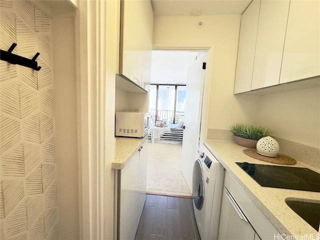 clothes washing area featuring washer and dryer, cabinet space, dark wood-style flooring, and a sink