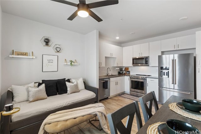 kitchen with tasteful backsplash, dark countertops, open floor plan, stainless steel appliances, and a sink