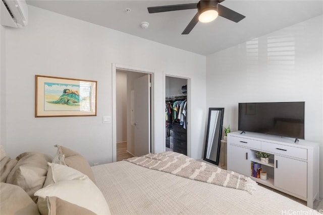 bedroom featuring an AC wall unit, a spacious closet, a closet, and a ceiling fan