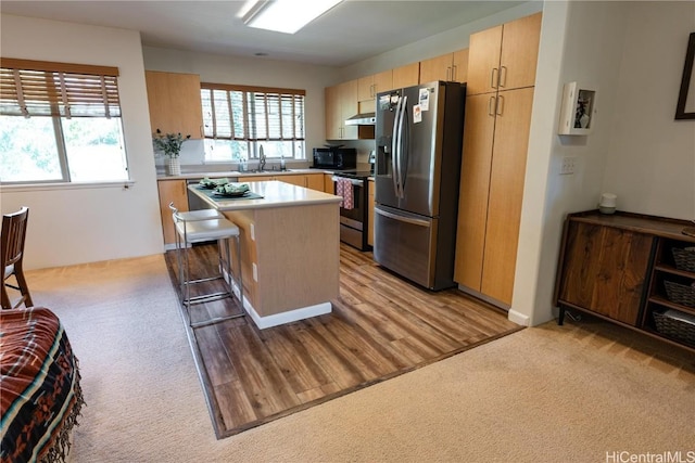 kitchen with appliances with stainless steel finishes, light colored carpet, plenty of natural light, and under cabinet range hood