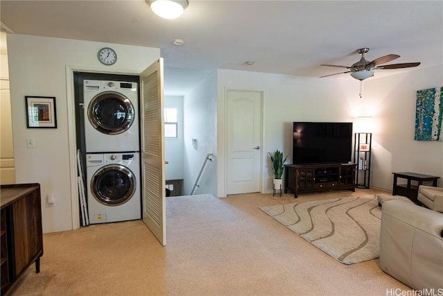 clothes washing area featuring stacked washing maching and dryer, ceiling fan, laundry area, and carpet flooring