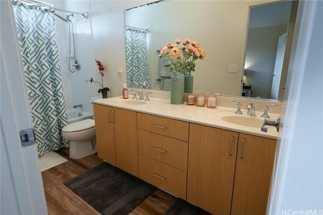 bathroom featuring double vanity, toilet, a sink, and wood finished floors