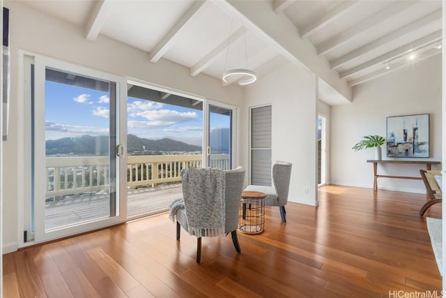 sitting room with high vaulted ceiling, a mountain view, wood finished floors, baseboards, and beam ceiling