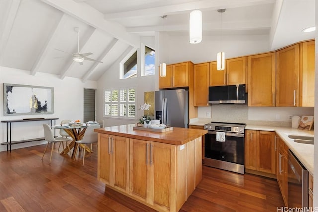 kitchen featuring appliances with stainless steel finishes, a center island, dark wood-style flooring, and beamed ceiling