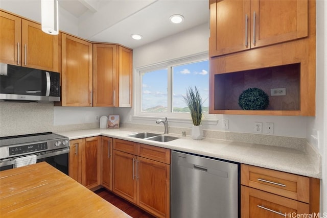 kitchen featuring recessed lighting, dark wood-style flooring, a sink, appliances with stainless steel finishes, and brown cabinetry