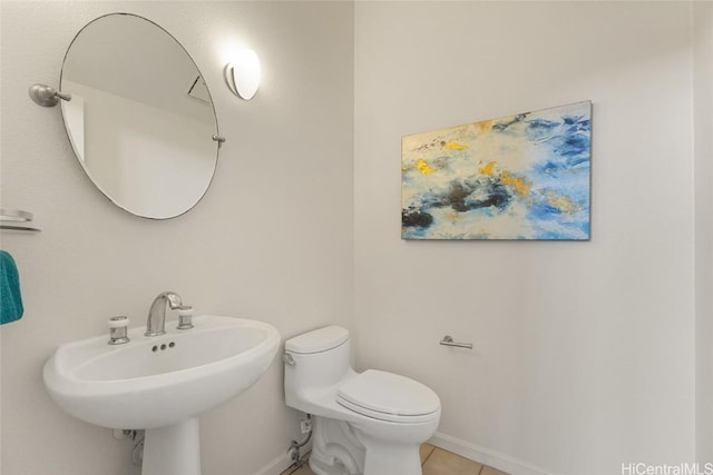 half bath featuring baseboards, a sink, toilet, and tile patterned floors