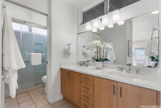 bathroom featuring double vanity, a stall shower, a sink, and tile patterned floors