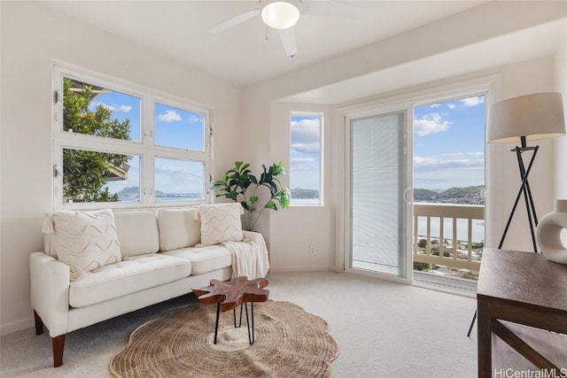 living area featuring carpet, baseboards, and ceiling fan