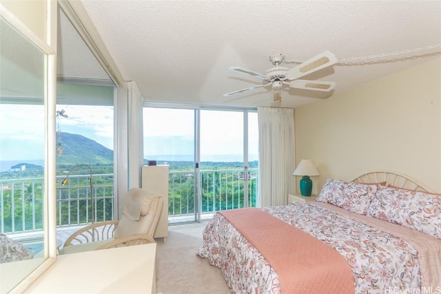 bedroom featuring a textured ceiling, ceiling fan, expansive windows, and carpet flooring