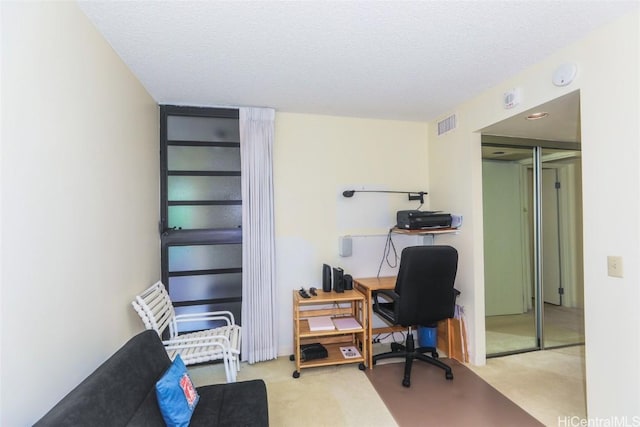 office area with carpet, visible vents, and a textured ceiling