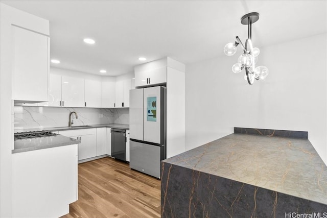 kitchen featuring light wood-style floors, freestanding refrigerator, white cabinetry, a sink, and dishwasher