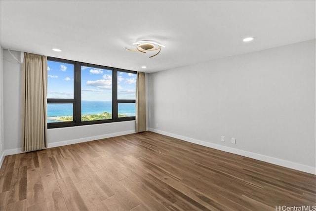 spare room featuring baseboards, wood finished floors, and recessed lighting