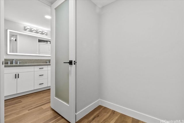 bathroom with double vanity, a sink, baseboards, and wood finished floors