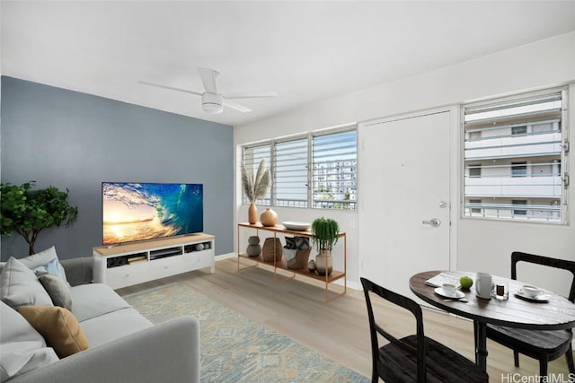 living area featuring light wood-style floors, ceiling fan, and baseboards